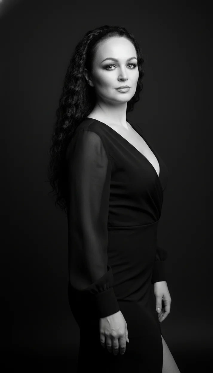 Женщина в студии в чёрном платье полуоборот